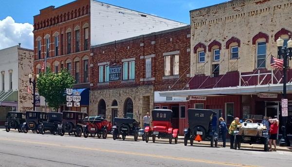 Old cars lined up in front of old buildings